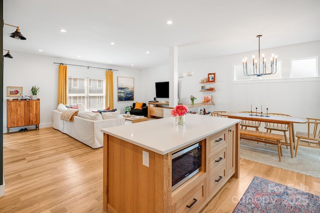 304 Magnolia Ridge Rd, Swannanoa, NC 28778 - kitchen with stainless steel microwave, a chandelier, light wood-style floors, a kitchen island, and light countertops