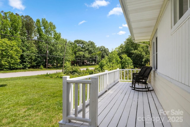 wooden terrace featuring a yard, covered porch, and view of scattered trees
