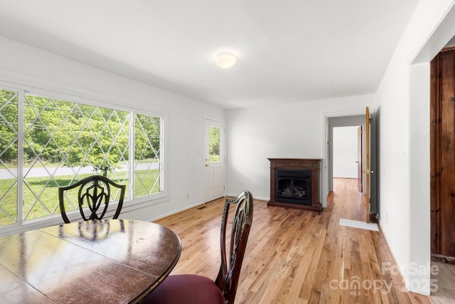 dining room with light wood-style floors, a fireplace, and baseboards