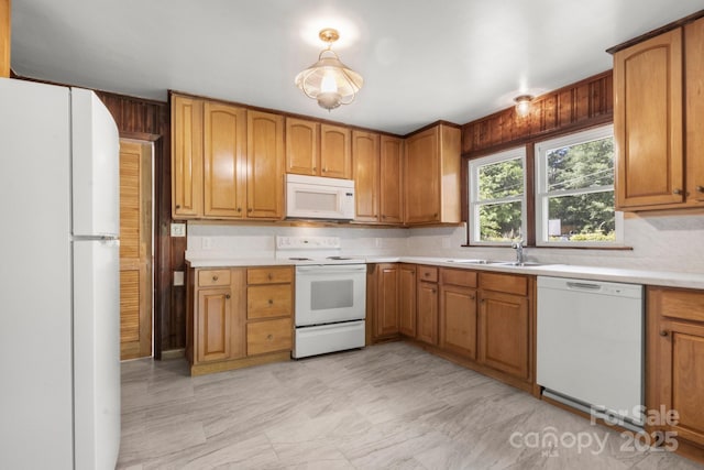kitchen with white appliances, a sink, light countertops, brown cabinets, and decorative backsplash