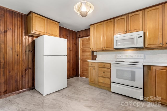 kitchen featuring white appliances, light marble finish flooring, light countertops, wooden walls, and brown cabinets