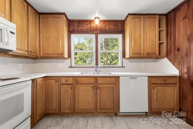 kitchen featuring white appliances, a sink, tasteful backsplash, and brown cabinetry