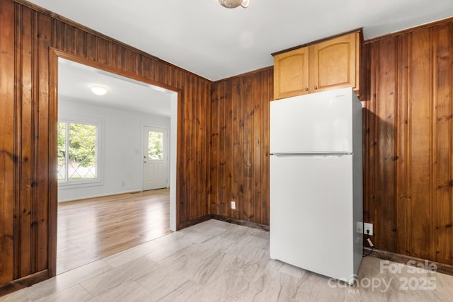 kitchen with freestanding refrigerator, wood walls, and baseboards