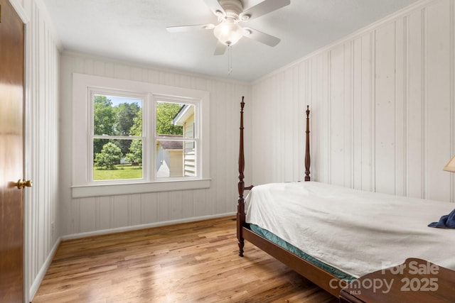 bedroom featuring wood finished floors, baseboards, ornamental molding, and a ceiling fan