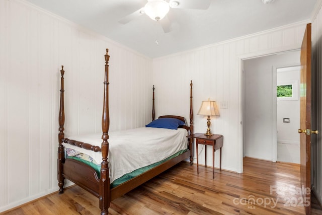 bedroom featuring crown molding, wood finished floors, a ceiling fan, and baseboards