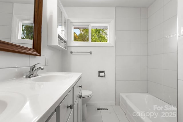 bathroom with toilet, double vanity, and baseboards