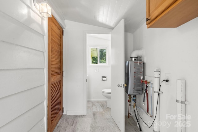 bathroom with toilet, vaulted ceiling, and marble look tile flooring