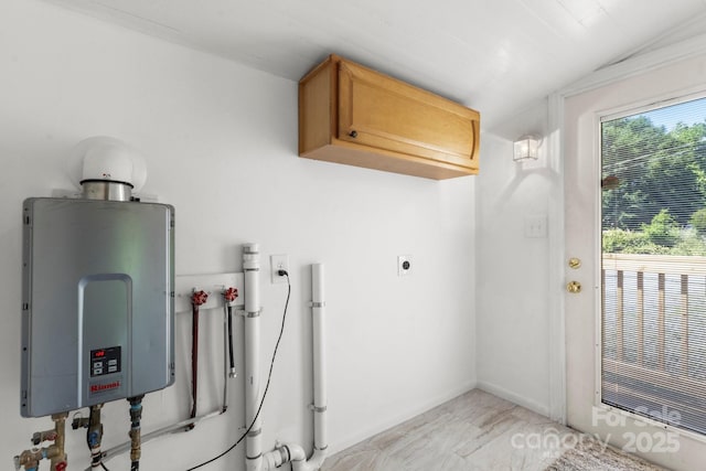 clothes washing area featuring cabinet space, hookup for a washing machine, and tankless water heater