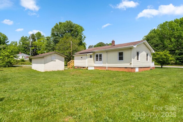 back of property featuring a chimney, a yard, and crawl space