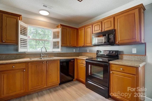 kitchen with black appliances, a sink, light wood-type flooring, brown cabinets, and a textured ceiling