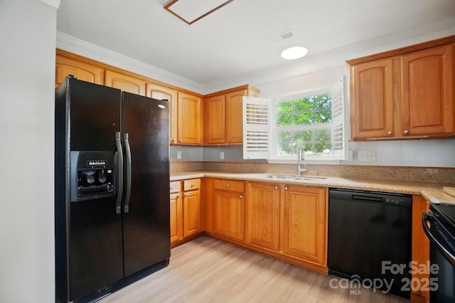 kitchen featuring black appliances, a sink, light wood finished floors, light countertops, and brown cabinets