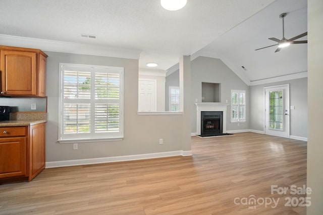 unfurnished living room with a ceiling fan, light wood finished floors, healthy amount of natural light, lofted ceiling, and crown molding
