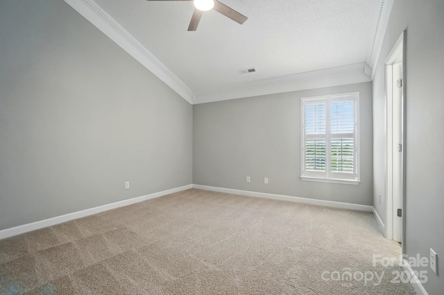 carpeted empty room featuring crown molding, a ceiling fan, and baseboards