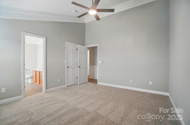 unfurnished bedroom featuring carpet flooring, baseboards, high vaulted ceiling, connected bathroom, and a ceiling fan