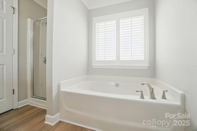 full bathroom with wood finished floors, a bath, and a stall shower