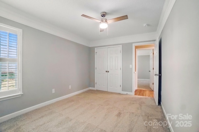 unfurnished bedroom with carpet floors, multiple windows, a closet, and baseboards