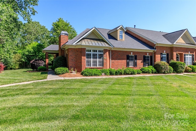 view of front of home featuring a shingled roof, brick siding, a chimney, and a front yard