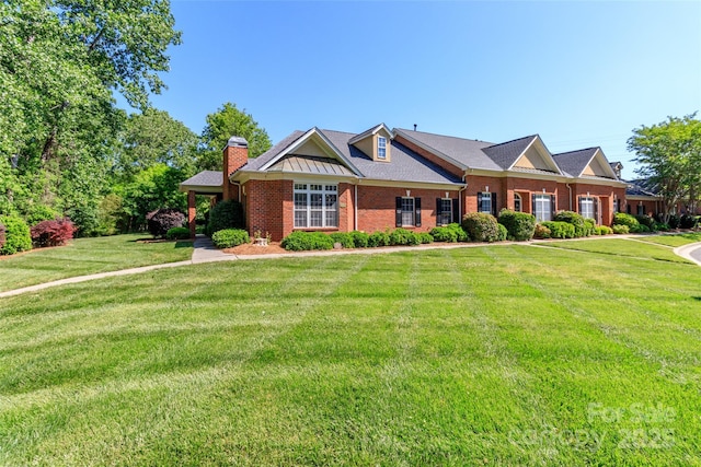 view of front of house with a front lawn, a chimney, and brick siding