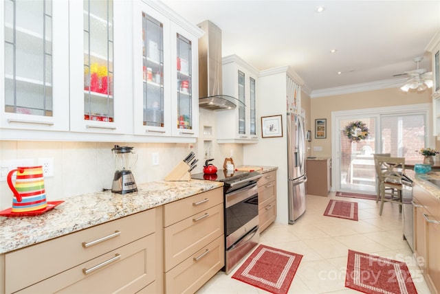 kitchen with wall chimney exhaust hood, appliances with stainless steel finishes, light stone counters, crown molding, and a ceiling fan