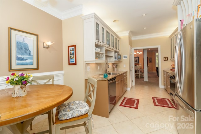 kitchen featuring a sink, stainless steel appliances, ornamental molding, light tile patterned flooring, and glass insert cabinets