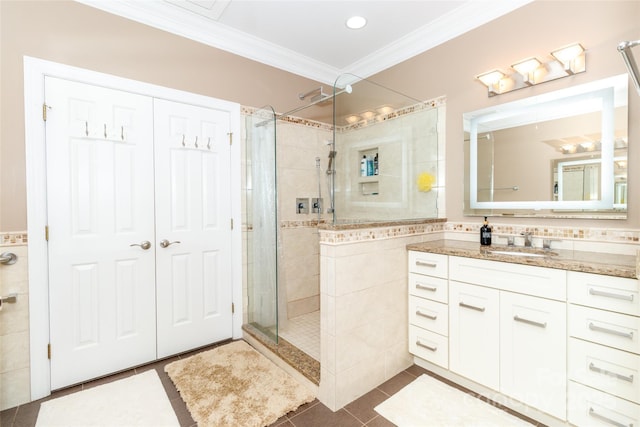 full bath with tile walls, vanity, tile patterned floors, crown molding, and a shower stall