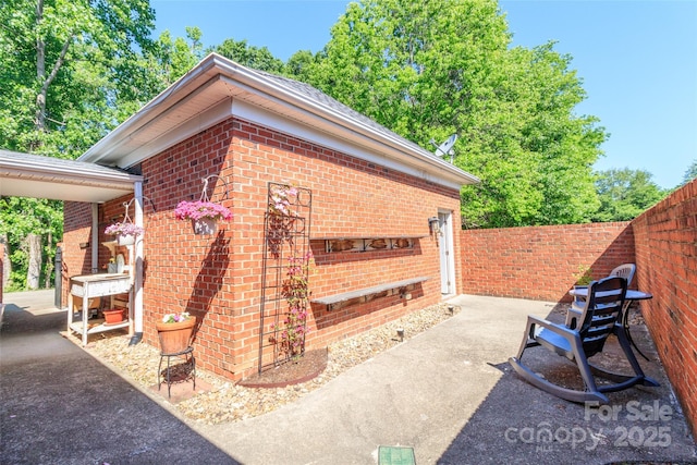 view of side of property with brick siding, fence, and a patio area