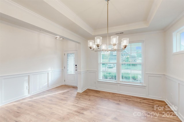 unfurnished dining area featuring a tray ceiling, visible vents, a decorative wall, a chandelier, and a wainscoted wall