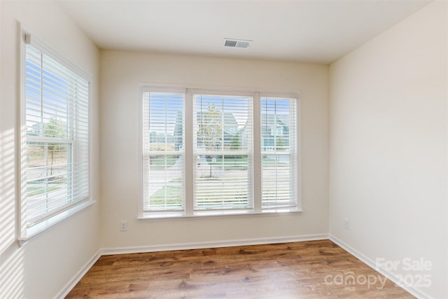 spare room featuring visible vents, wood finished floors, and baseboards