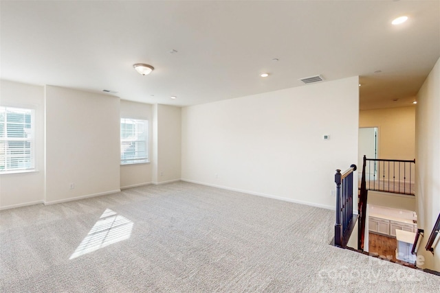 empty room featuring light carpet, baseboards, visible vents, and recessed lighting