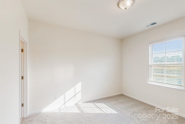 carpeted spare room with visible vents and baseboards