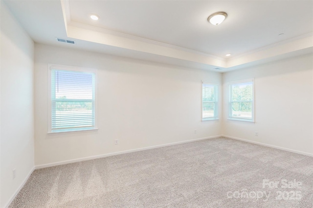 unfurnished room featuring light colored carpet, visible vents, crown molding, a tray ceiling, and baseboards