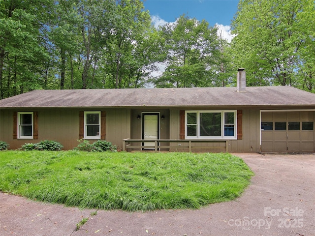 ranch-style home featuring a chimney, driveway, roof with shingles, and a garage