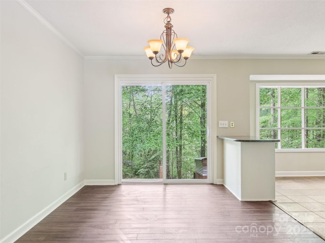 unfurnished dining area featuring baseboards, a wealth of natural light, a notable chandelier, and visible vents
