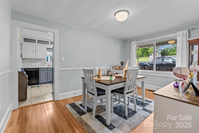 dining area with light wood finished floors, ornamental molding, baseboards, and visible vents