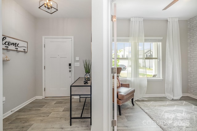 entryway with baseboards, a notable chandelier, and wood finished floors