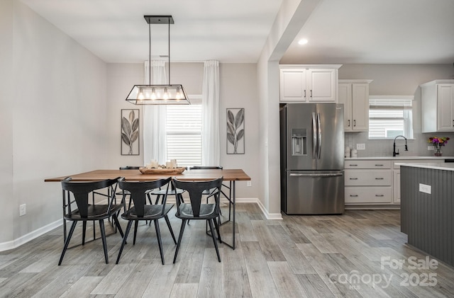 kitchen featuring a sink, light wood-type flooring, stainless steel fridge with ice dispenser, and light countertops