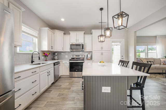 kitchen with light wood-style floors, appliances with stainless steel finishes, a kitchen bar, and a sink