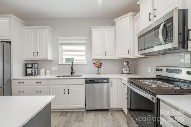 kitchen featuring white cabinets, light countertops, stainless steel appliances, and a sink