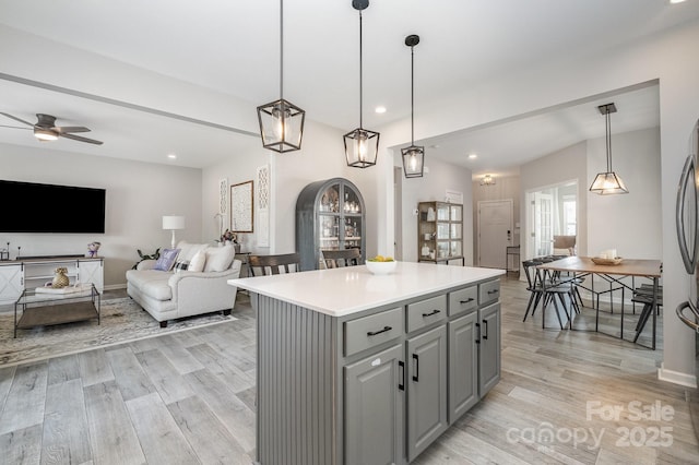 kitchen featuring light wood finished floors, ceiling fan, light countertops, a center island, and gray cabinetry
