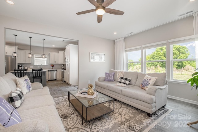 living area featuring light wood-type flooring, recessed lighting, ceiling fan, and visible vents