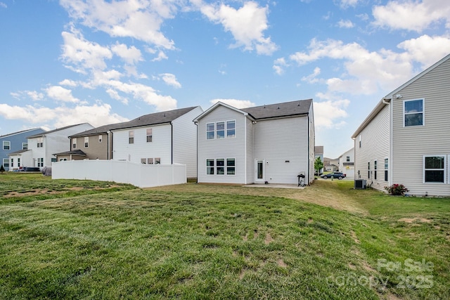 rear view of property featuring central air condition unit, fence, a residential view, and a lawn