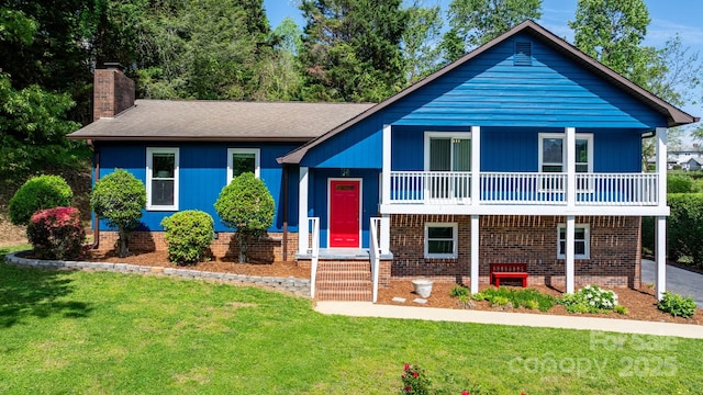 split level home with a chimney, a front yard, brick siding, and a balcony