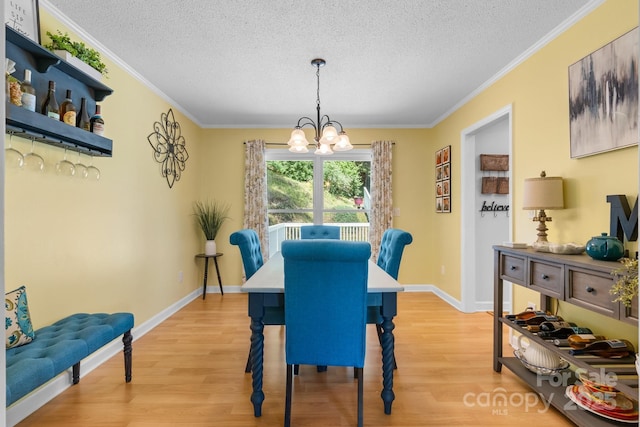 dining room with light wood finished floors, an inviting chandelier, and a textured ceiling
