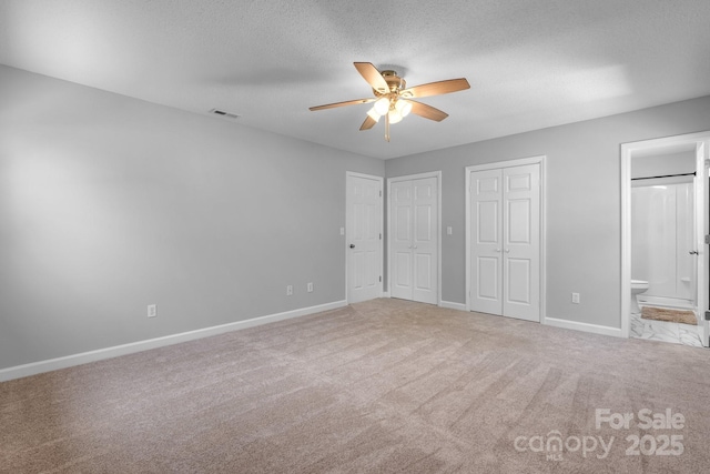 unfurnished bedroom with two closets, carpet flooring, baseboards, and visible vents