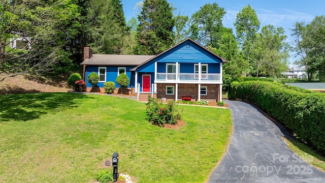 split level home featuring a chimney, a front yard, brick siding, and aphalt driveway