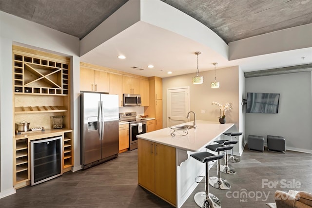 kitchen with appliances with stainless steel finishes, a kitchen bar, a peninsula, a sink, and recessed lighting