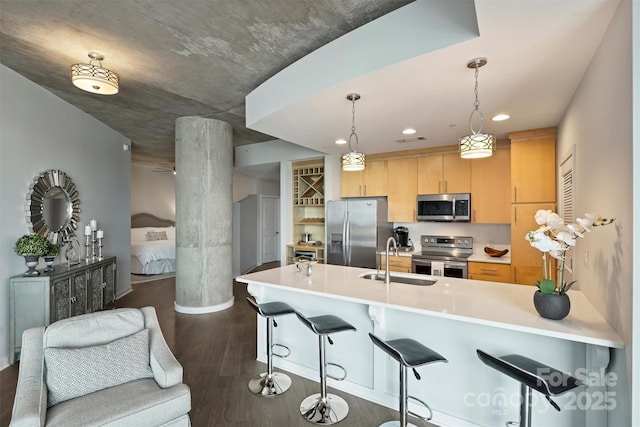 kitchen featuring stainless steel appliances, a sink, a breakfast bar, dark wood-style floors, and a peninsula