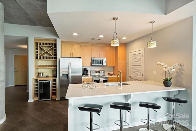 kitchen with appliances with stainless steel finishes, a sink, light brown cabinetry, wine cooler, and a kitchen bar