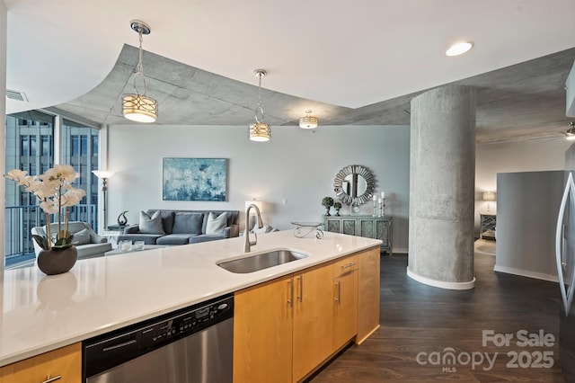 kitchen with stainless steel appliances, a sink, open floor plan, decorative columns, and dark wood-type flooring