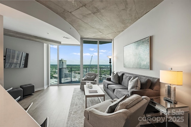 living area with expansive windows, wood finished floors, and baseboards